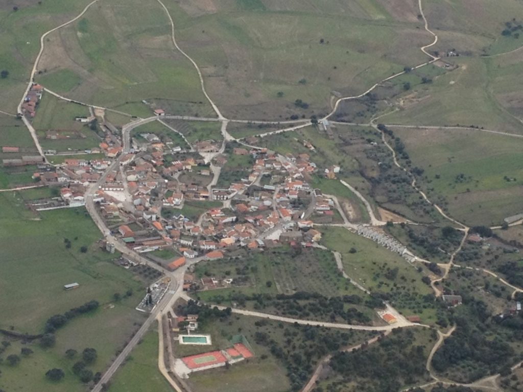 Vista aérea de Garciotum: el casco urbano de tejados rojos rodeado de campos, caminos y dehesa