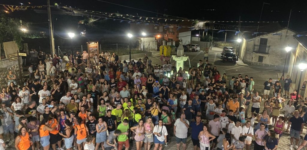 Multitud de vecinos y visitantes en la plaza de Garciotum, de noche y con banderines, durante las fiestas de julio